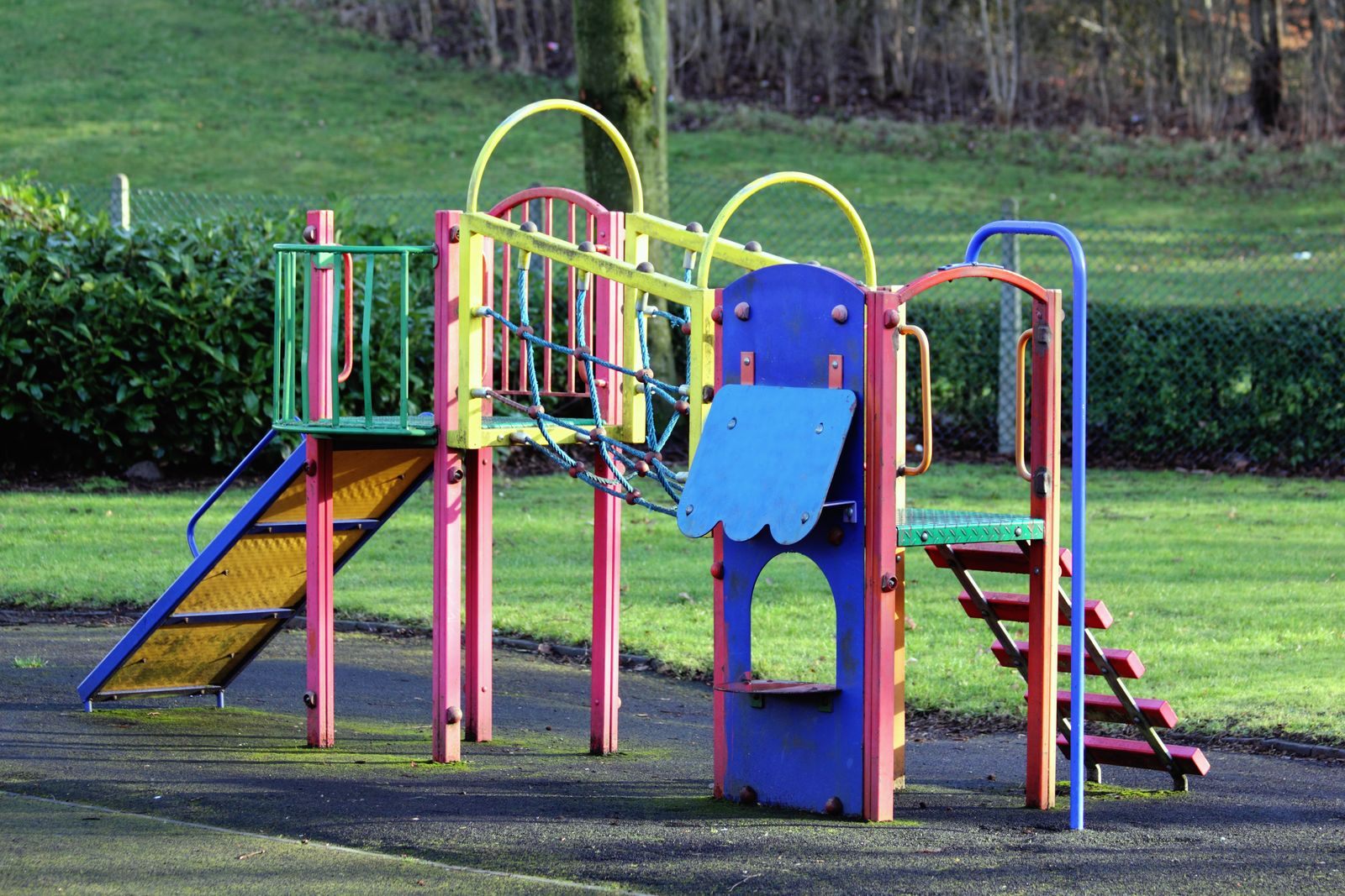 A brightly painted playground with slides and climbing frames on a grassy lawn, like the play areas at the Acreage park and the district’s neighborhood parks